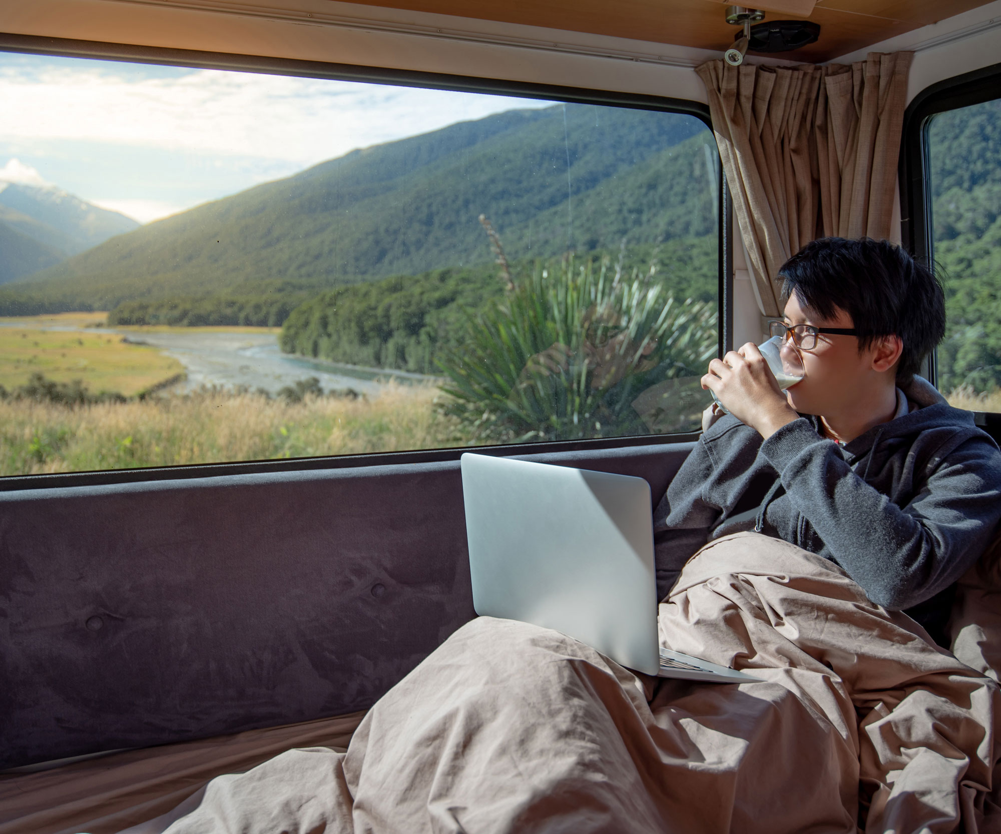man on laptop inside campervan at remote location